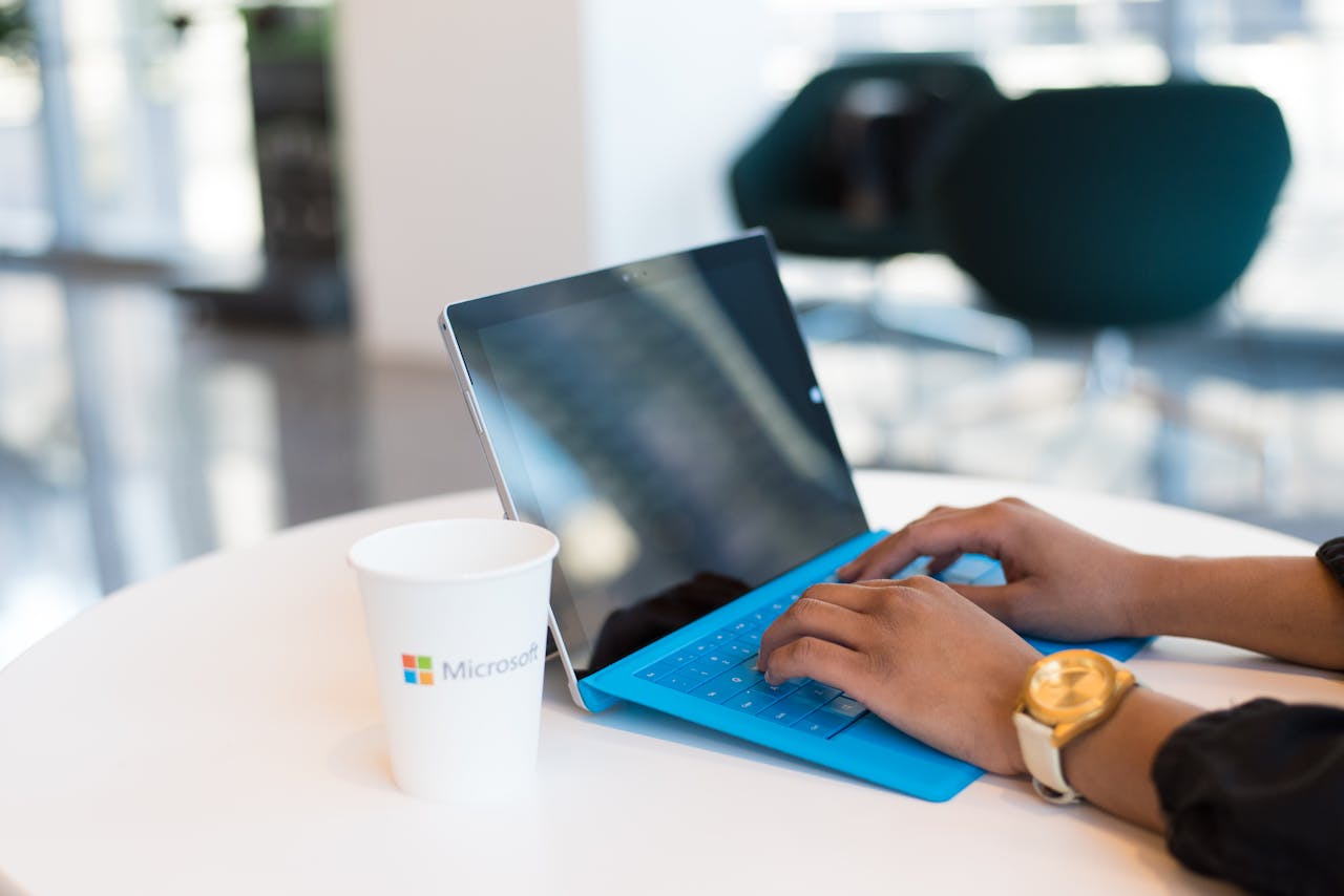 Home Hands typing on a blue keyboard with a branded cup on a table.