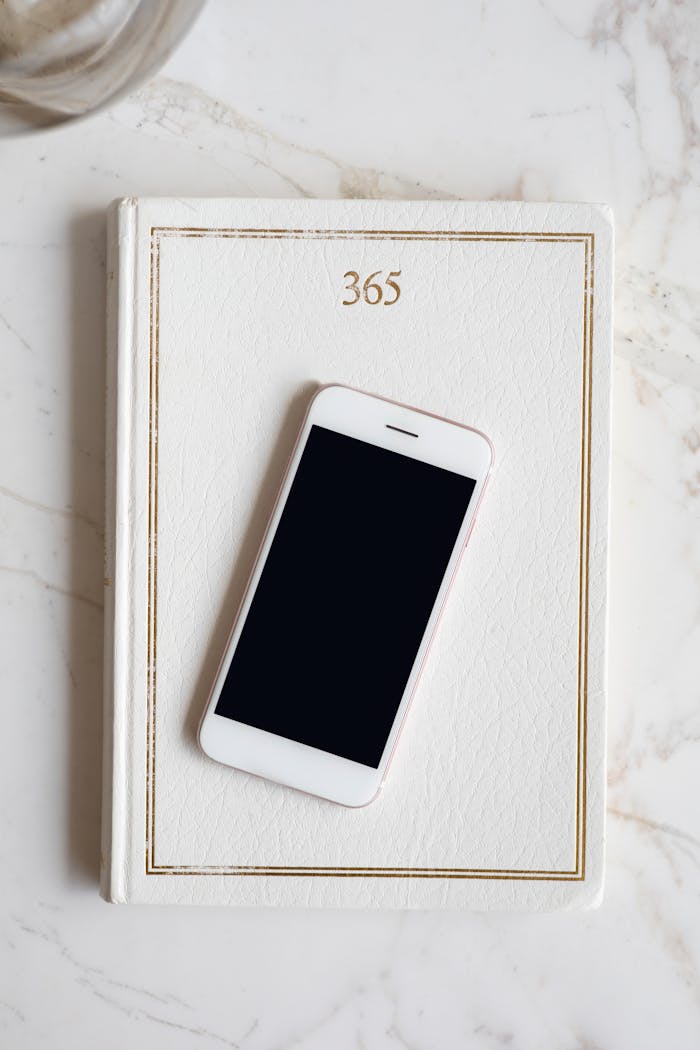 Home A minimalist flat lay featuring a smartphone on a planner with a marble background.